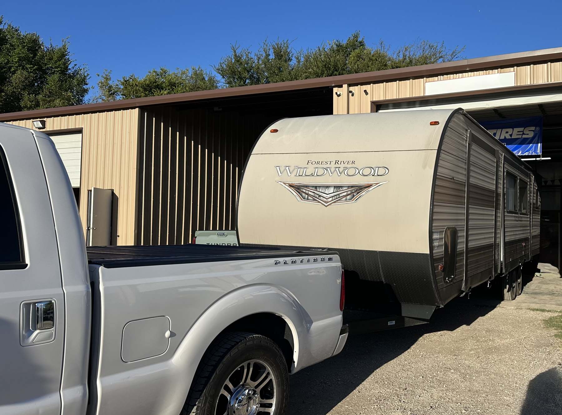 Travel trailer hitched to a pickup outside the RepairAnyRV shop in Princeton, TX